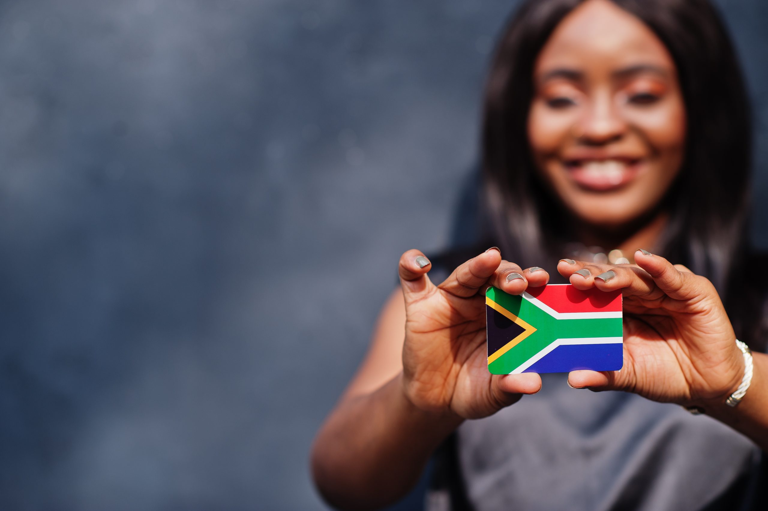 African woman hold small South Africa flag in hands.